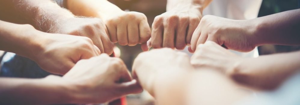 Close up of young people putting their hands together. Team with stack of hands showing unity and teamwork.